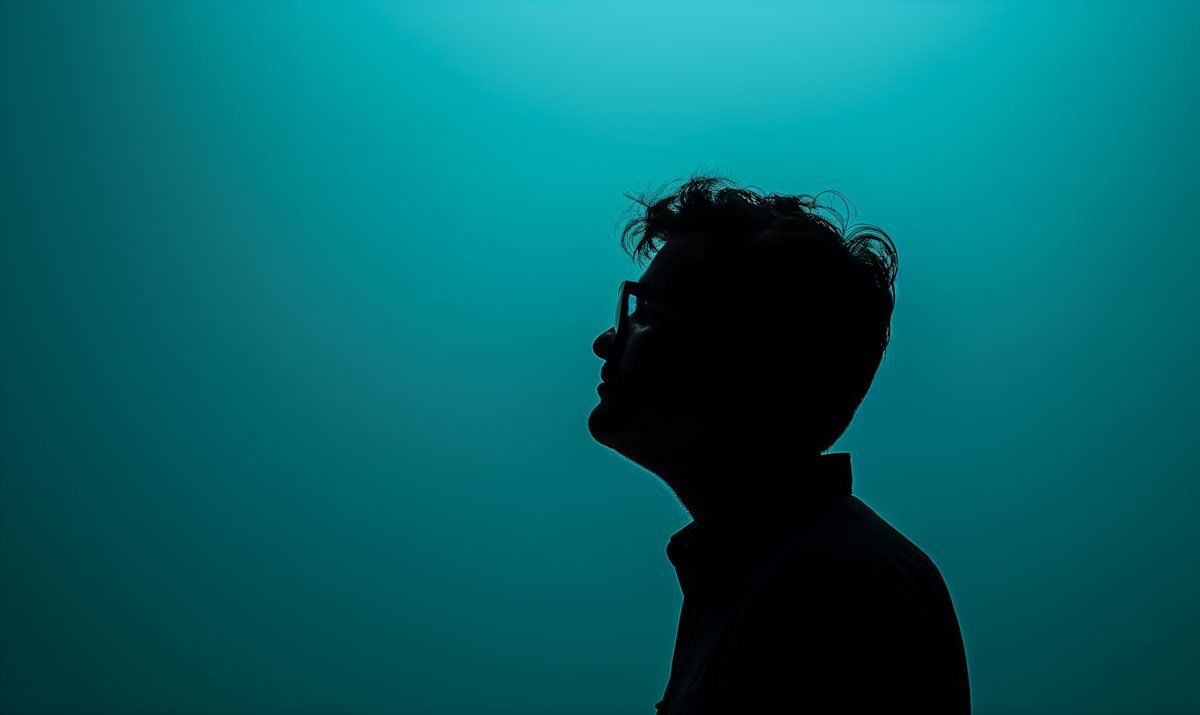 A solitary figure in silhouette against a deep teal-blue gradient — the contemplative quiet of starting again